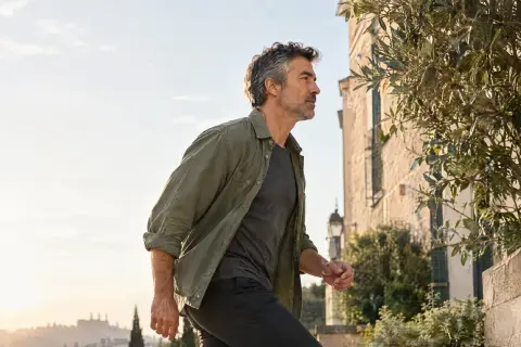 A man in his fifties walking up stone steps in the morning.